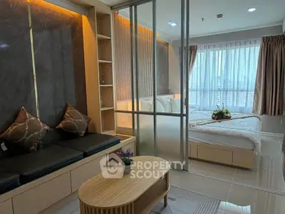 Modern studio apartment with glass partition, cozy seating, and natural light.