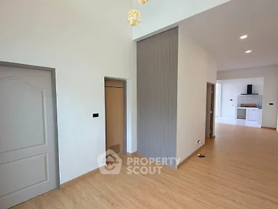 Spacious modern interior with open layout and stylish lighting, featuring wood flooring and sleek kitchen area.