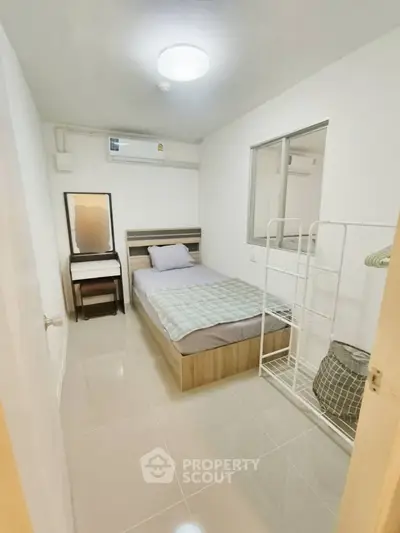 Cozy minimalist bedroom with modern furnishings and air conditioning, perfect for a comfortable living experience.
