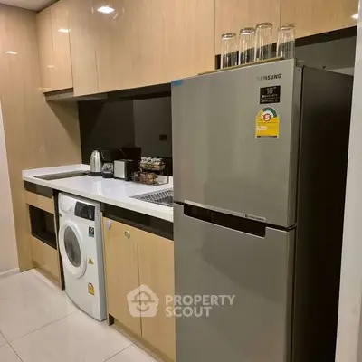 Modern kitchen with sleek appliances and washing machine in compact layout