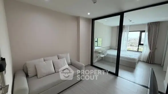 Modern apartment with glass partition separating living room and bedroom, featuring a cozy sofa and large window.