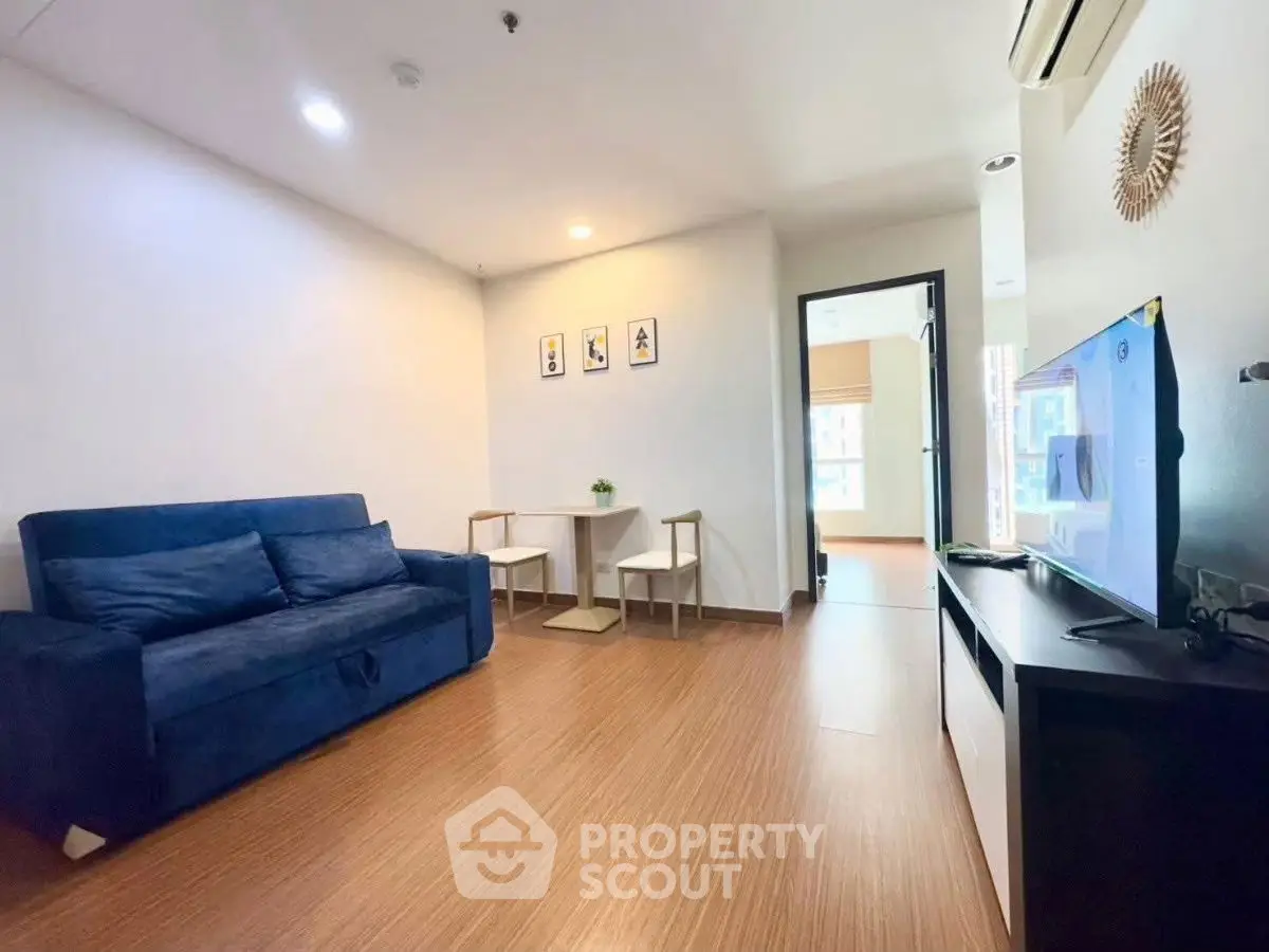 Modern living room with blue sofa and wall-mounted TV, featuring minimalist decor.