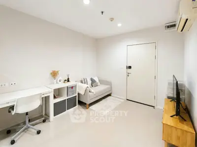 Modern living room with cozy sofa, TV, and workspace in a bright apartment.