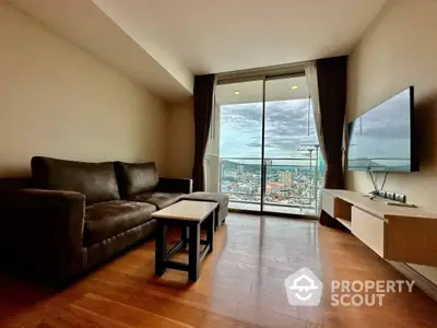 Spacious living room with polished hardwood floors, large windows offering a panoramic city view, and modern furnishings.