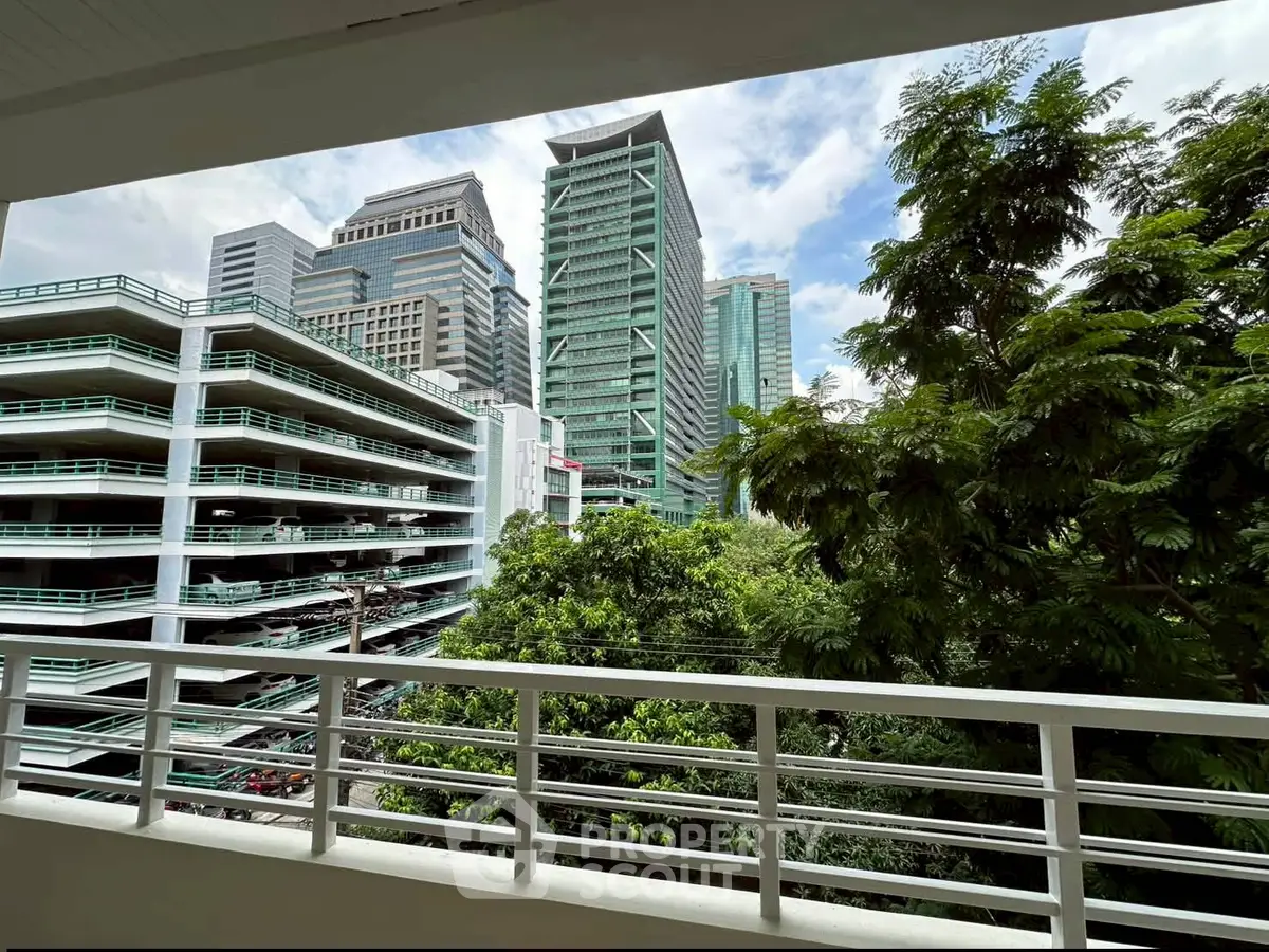 Stunning cityscape view from a balcony with lush greenery and modern buildings.