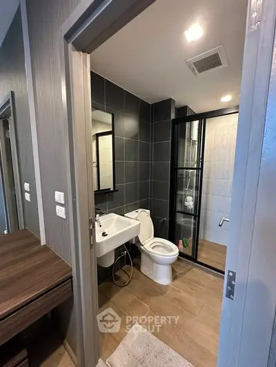 Modern bathroom with sleek black tiles and glass shower enclosure