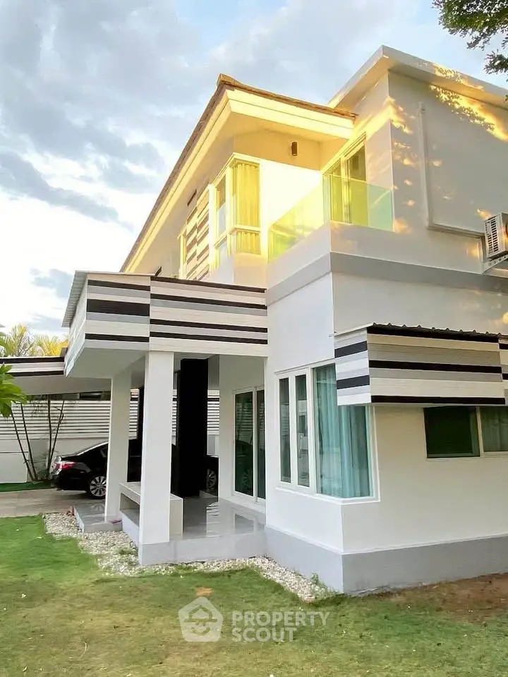 Modern two-story house with sleek design and large windows, surrounded by a lush green lawn.