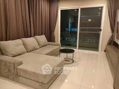 Modern living room with plush sofa and sliding glass doors leading to a balcony.