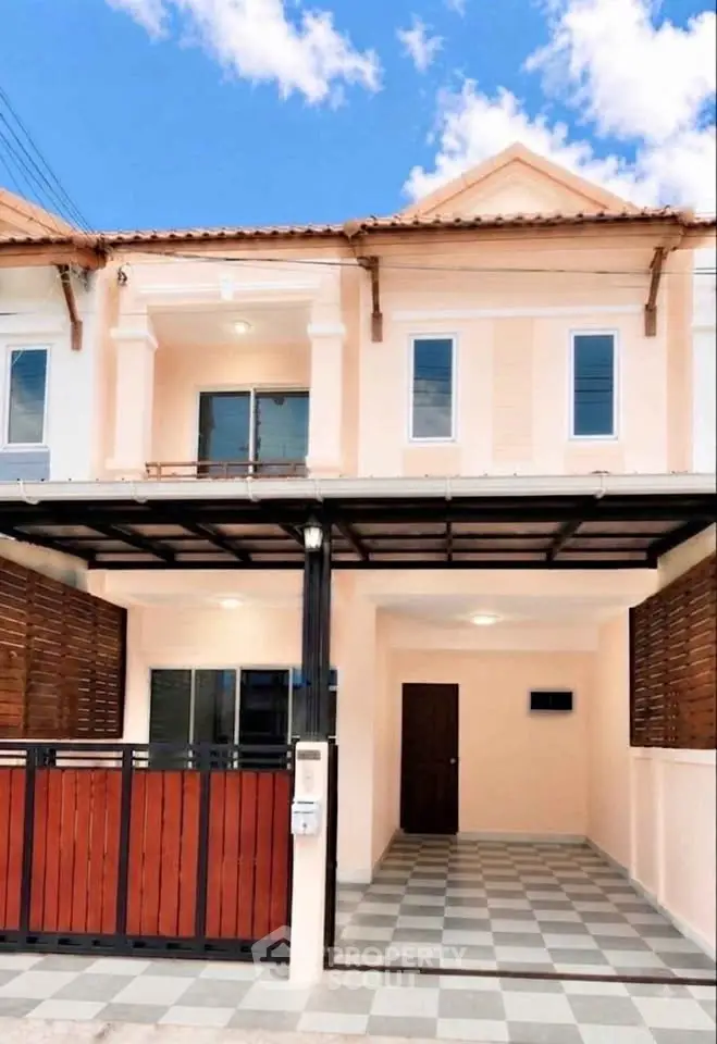 Charming townhouse with modern facade and spacious driveway under a clear blue sky.