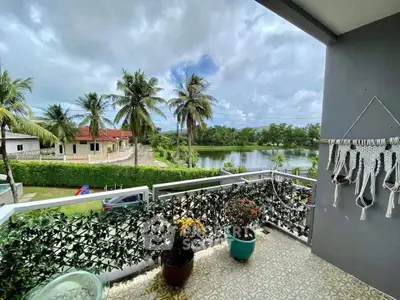 Charming balcony with lush greenery and serene water view, perfect for relaxation.