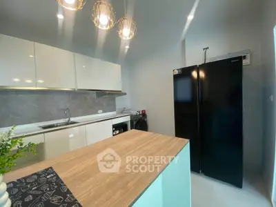 Modern kitchen with sleek cabinets, island, and black refrigerator