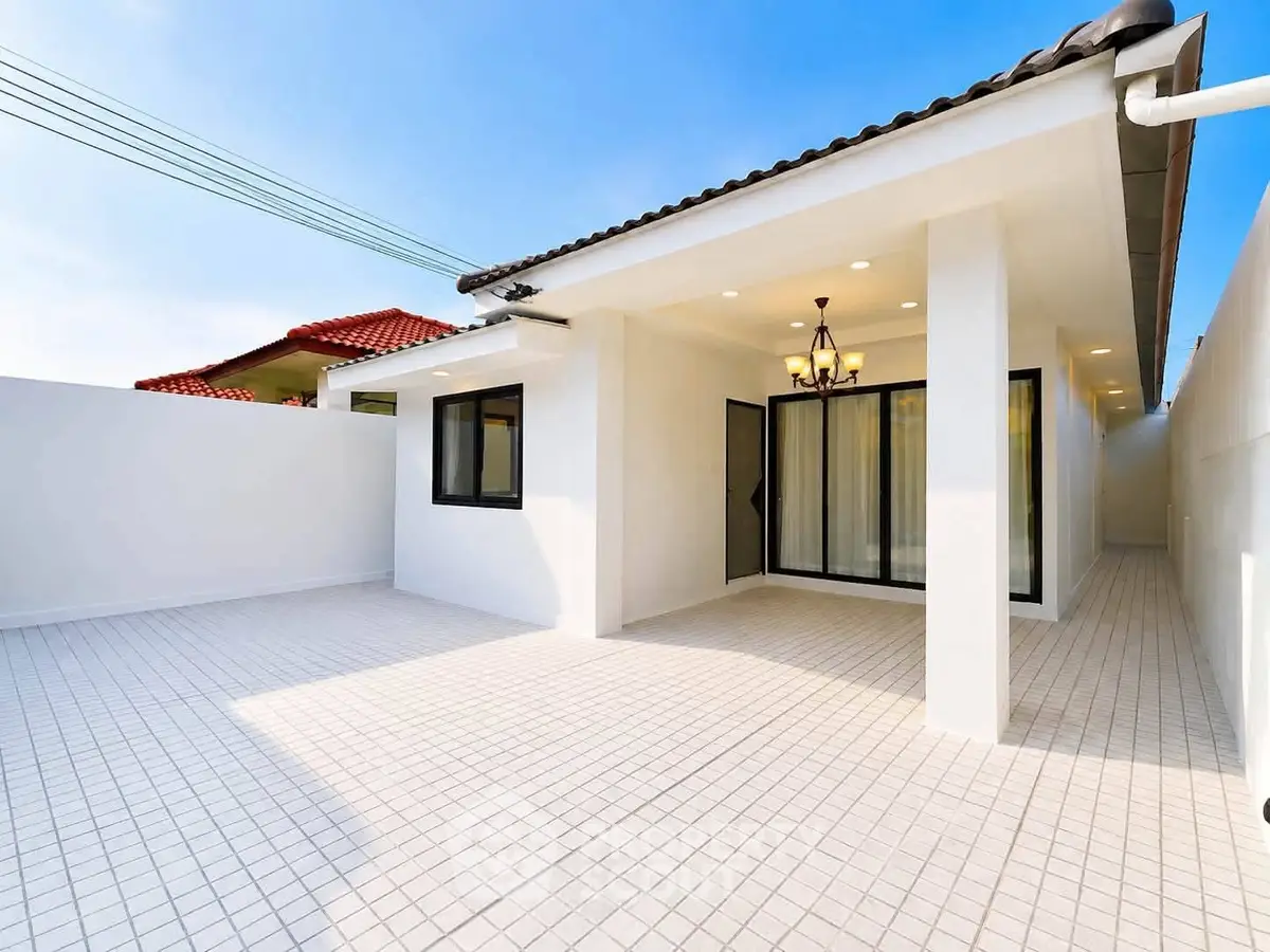 Modern white exterior with tiled patio and elegant lighting, perfect for outdoor gatherings.