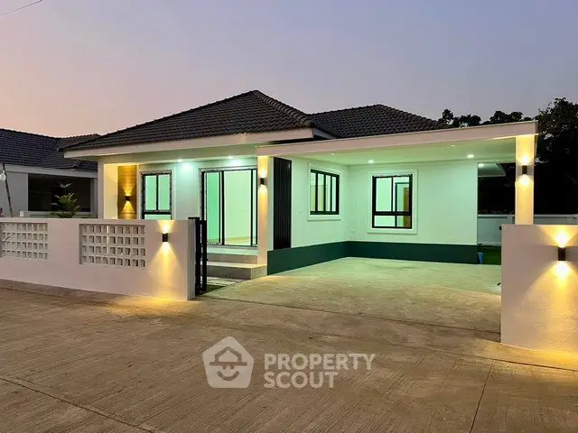 Modern single-story home with illuminated driveway and sleek exterior design.