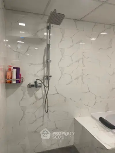 Modern bathroom with sleek shower and marble tiles, featuring a built-in bathtub.