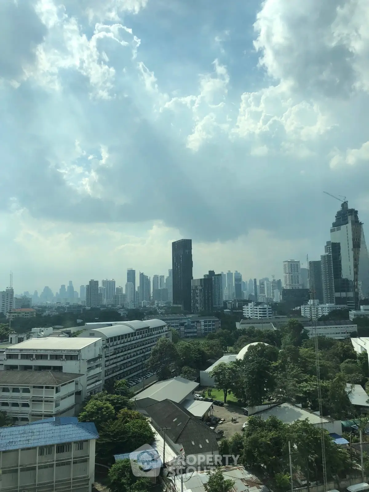 Stunning cityscape view with skyscrapers and lush greenery under a dramatic sky.