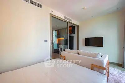 Modern studio apartment with open layout, featuring a cozy living area and a compact kitchen with appliances.
