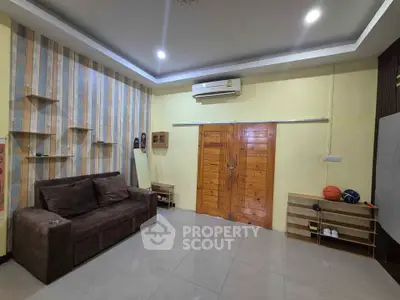 Modern living room with stylish decor and air conditioning, featuring a cozy sofa and wooden accents.