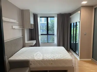 Modern bedroom with large window and natural light in a stylish apartment.