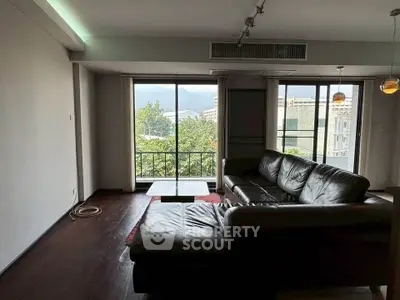 Spacious living room with leather sofa and scenic balcony view