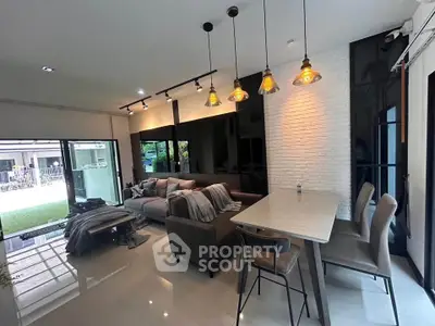 Modern living room with stylish lighting and open layout, featuring sleek furniture and large windows.