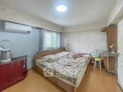 Cozy bedroom with large bed, air conditioning, and natural light from window.