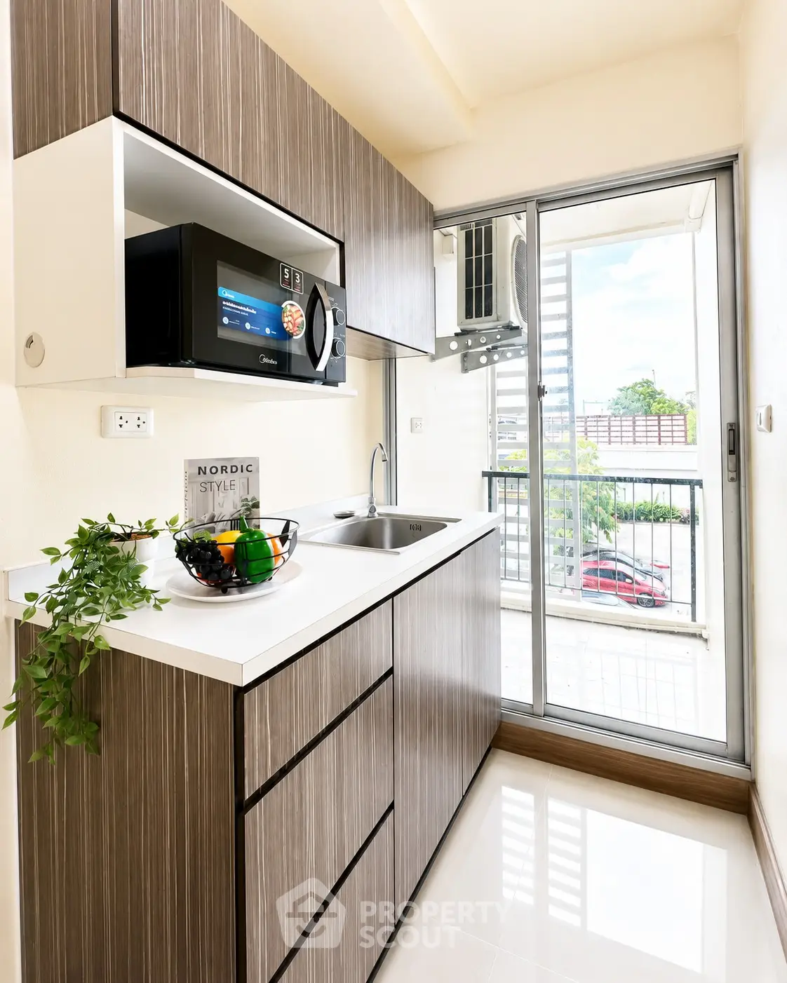 Modern kitchen with sleek cabinetry and balcony view, featuring built-in microwave and stylish decor.