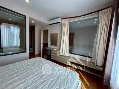 Spacious bedroom with large window and modern furnishings in a stylish apartment.