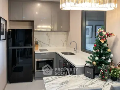 Modern kitchen with sleek appliances and festive decor, featuring a marble countertop and compact layout.