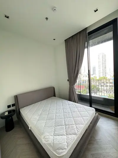 Modern bedroom with city view and balcony access, featuring a stylish bed and elegant curtains.