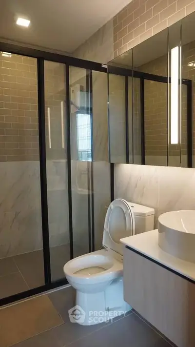 Modern bathroom with glass shower and sleek fixtures in contemporary apartment.