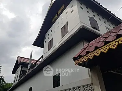 Charming traditional-style building with ornate roof details and cloudy sky backdrop.