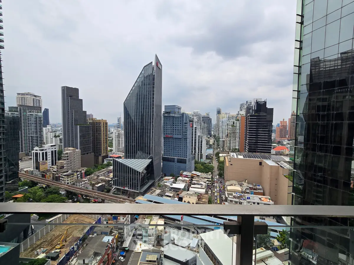 Stunning cityscape view from a high-rise balcony overlooking modern skyscrapers and urban landscape.