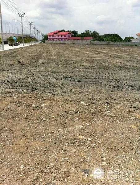 Expansive vacant lot ready for development, showcasing fertile land with a clear sky and potential for various construction projects, near urban amenities.