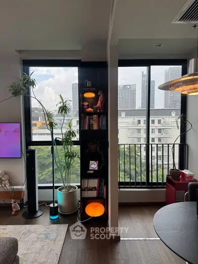 Modern living room with large windows and city view, featuring stylish decor and indoor plants.