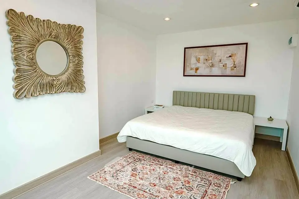 Elegant bedroom with stylish decor and cozy ambiance, featuring a large bed and artistic wall mirror.