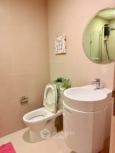 Modern bathroom with sleek fixtures and stylish decor, featuring a round mirror and contemporary sink.