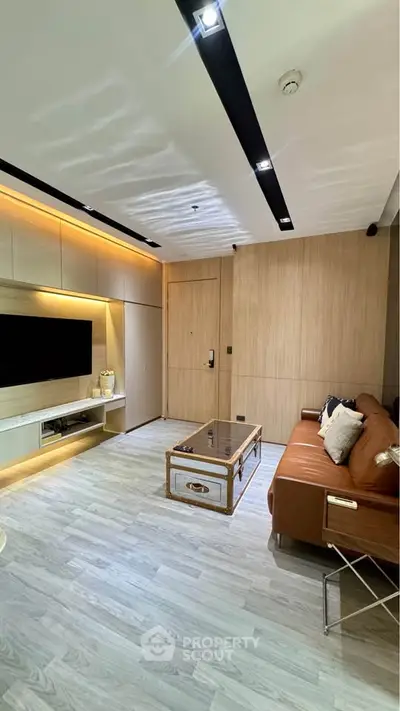 Modern living room with sleek design, featuring a leather sofa, stylish coffee table, and built-in TV unit.