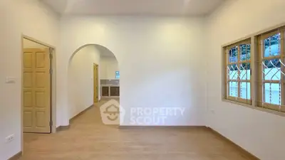 Spacious interior with arched doorway and wooden flooring, ideal for modern living.