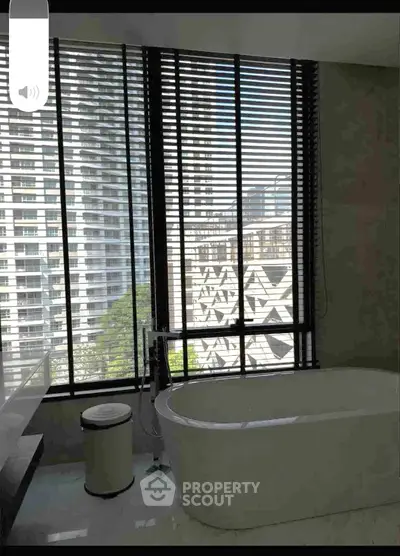 Luxurious bathroom with a modern bathtub and city view through large windows.
