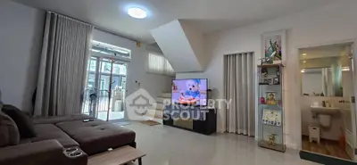 Spacious living room with modern decor and large TV, featuring open layout and natural light.