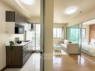 Modern open-layout apartment with sleek kitchen and cozy living area, featuring large windows for natural light.