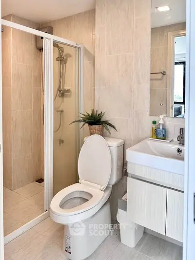 Modern bathroom with shower, toilet, and sink in a stylish apartment.
