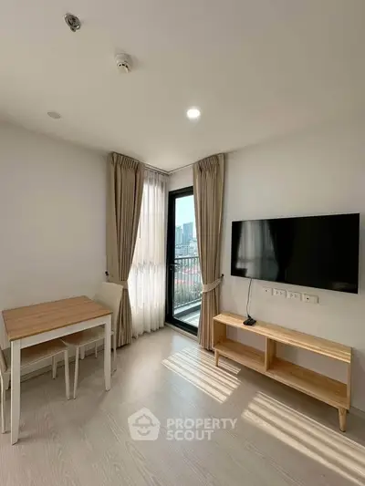 Modern living room with natural light, featuring a wall-mounted TV, wooden table, and balcony access.