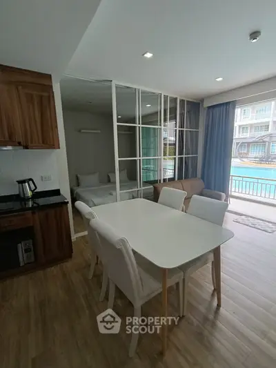 Modern open-plan living and dining area with pool view, featuring elegant furniture and wooden flooring.