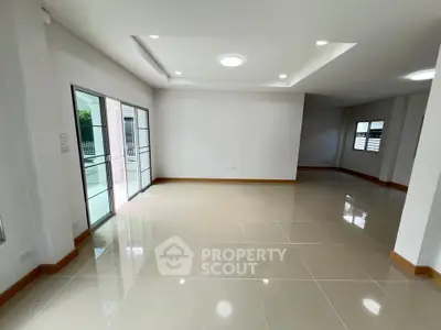 Spacious modern living room with large windows and glossy tiled floors