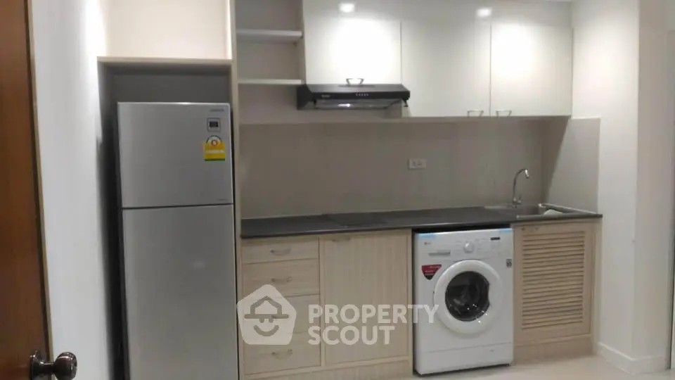 Modern kitchen with sleek appliances including fridge and washing machine, ideal for urban living.
