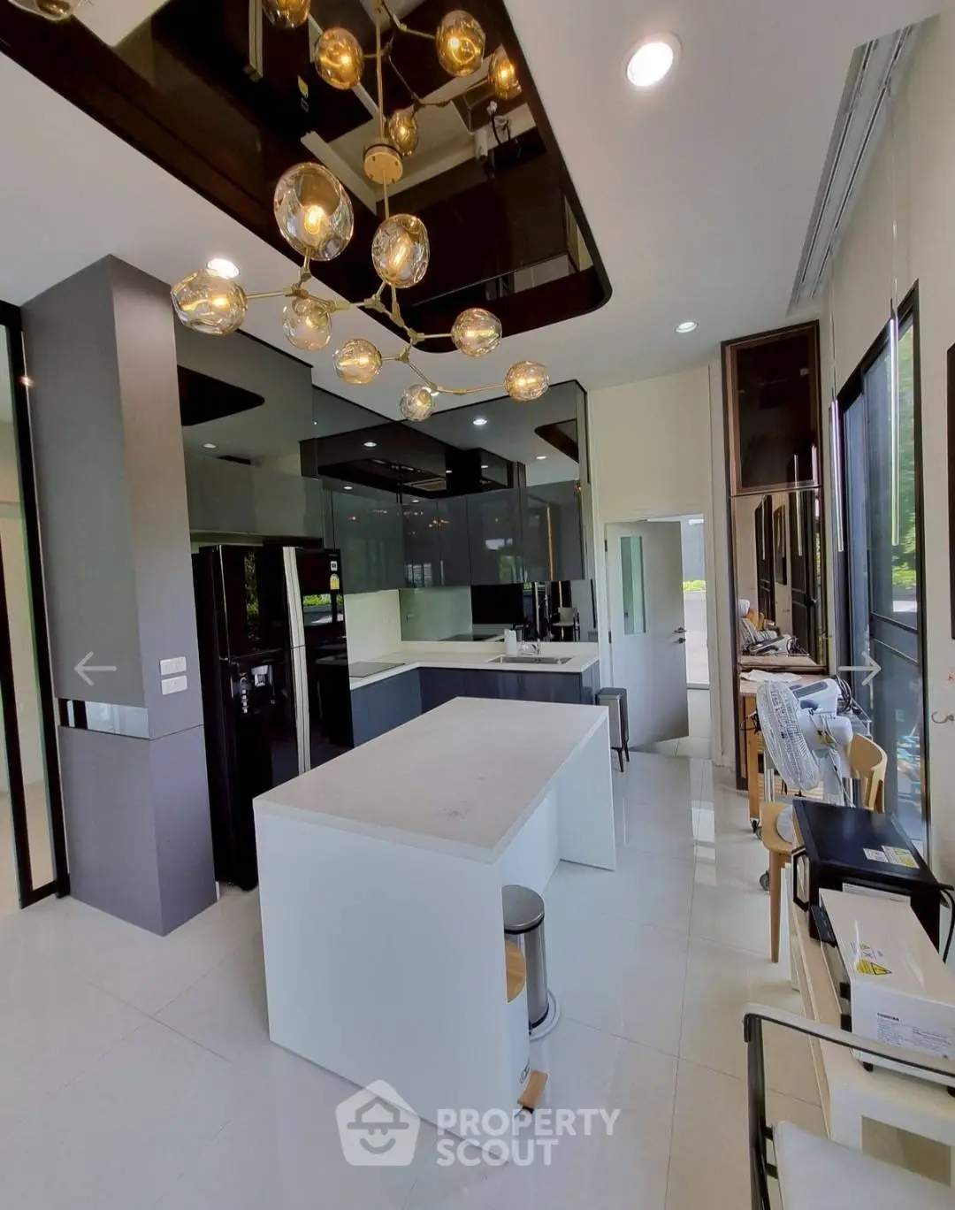 Modern kitchen with sleek design and island, featuring stylish lighting and large windows.