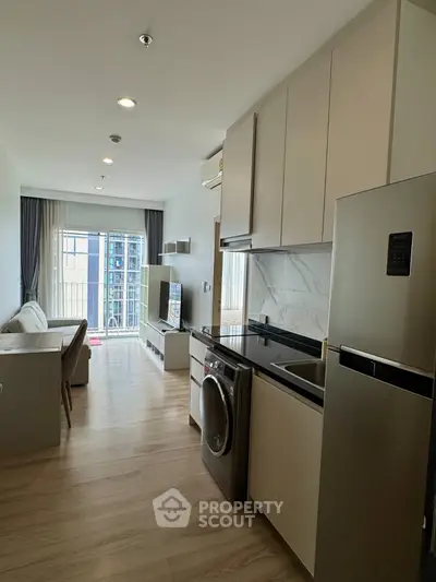 Modern open-layout kitchen and living room with sleek appliances and natural light.