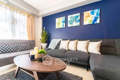 Stylish living room with modern decor, blue accent wall, and cozy seating area.