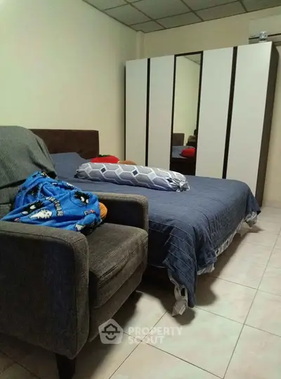 Cozy bedroom with modern wardrobe and comfortable seating area, perfect for relaxation.